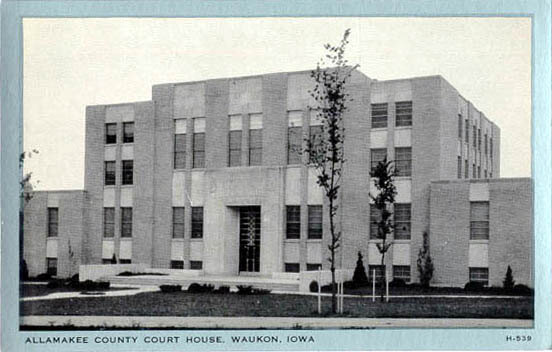 A black and white image of the Allamakee County Courthouse in Waukon, Iowa, featuring a symmetrical three-story building with minimal landscaping.